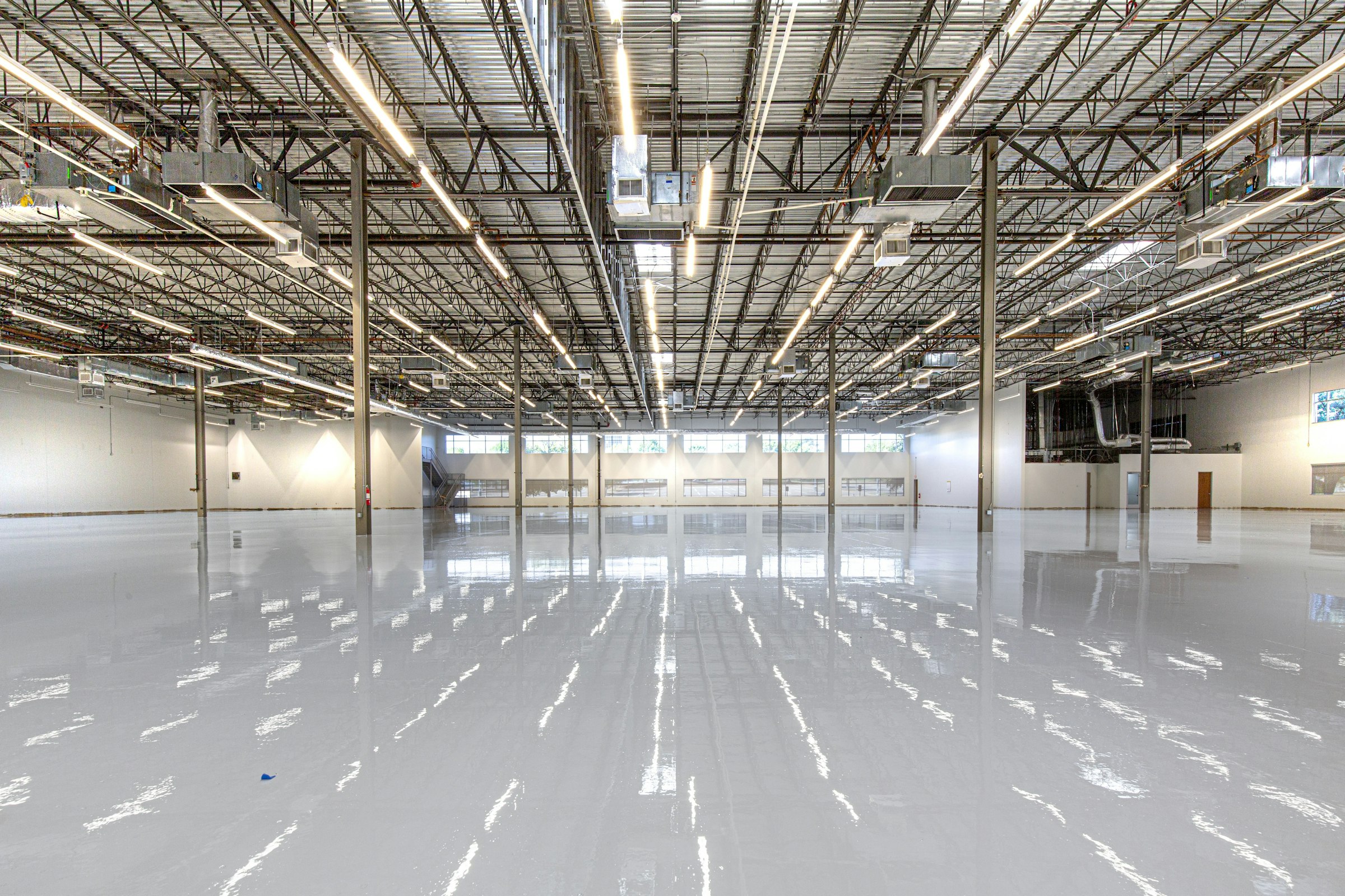 A freshly coated warehouse floor, glossy enough to mirror every ceiling light
